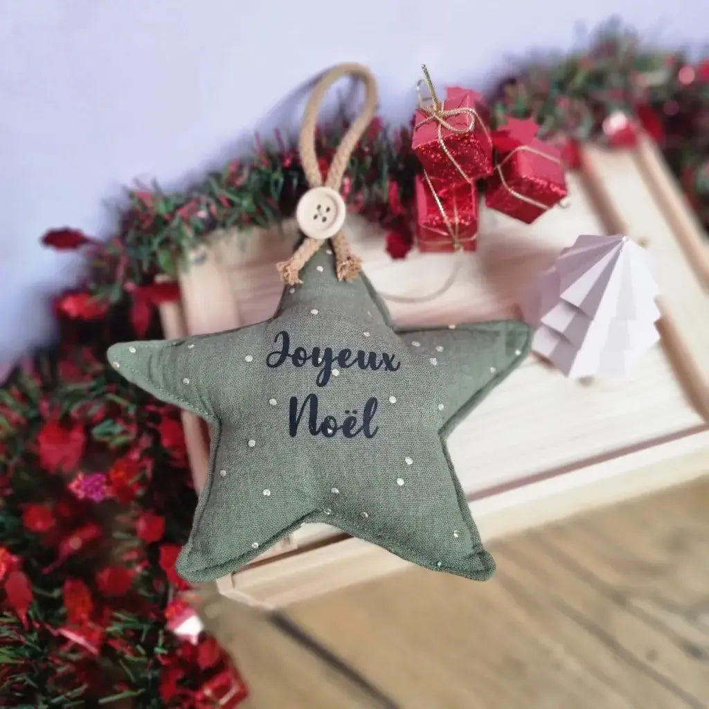 Etoile de Noël à suspendre en tissu double gaze de coton vert. Cette étoile de Noël est personnalisée avec l'inscription "Joyeux Noël" floquée en noir en son centre.