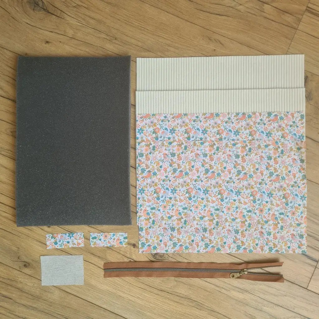 Kit "prêt à coudre" pour réaliser une housse pour tablette ou iPad en velours côtelé beige doublée avec un tissu à motif oiseaux et fleurs. Ce kit couture est composé de 2 plaques en mousse, de 2 pièces en velours côtelé beige, de 5 pièces en coton imprimé à motif oiseaux et fleurs et d'une fermeture éclair marron. La housse est personnalisable avec un prénom ou une inscription qui peut être floquée sur une étiquette en tissu coton et lin.