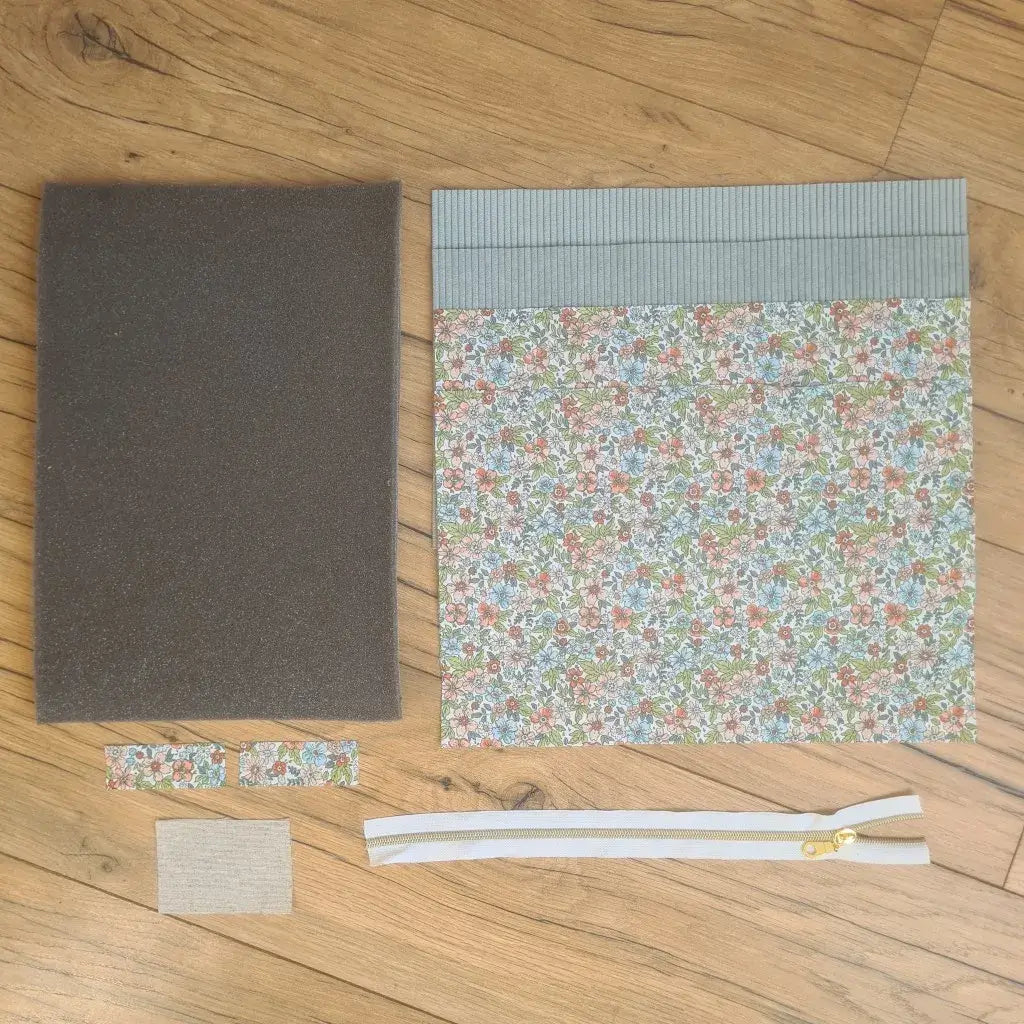 Kit "prêt à coudre" pour réaliser une housse pour tablette ou iPad en velours côtelé bleu clair doublée avec un tissu à motif fleurs. Ce kit couture est composé de 2 plaques en mousse, de 2 pièces en velours côtelé bleu clair, de 5 pièces en coton imprimé à motif fleurs et d'une fermeture éclair blanche. La housse est personnalisable avec un prénom ou une inscription qui peut être floquée sur une étiquette en tissu coton et lin.
