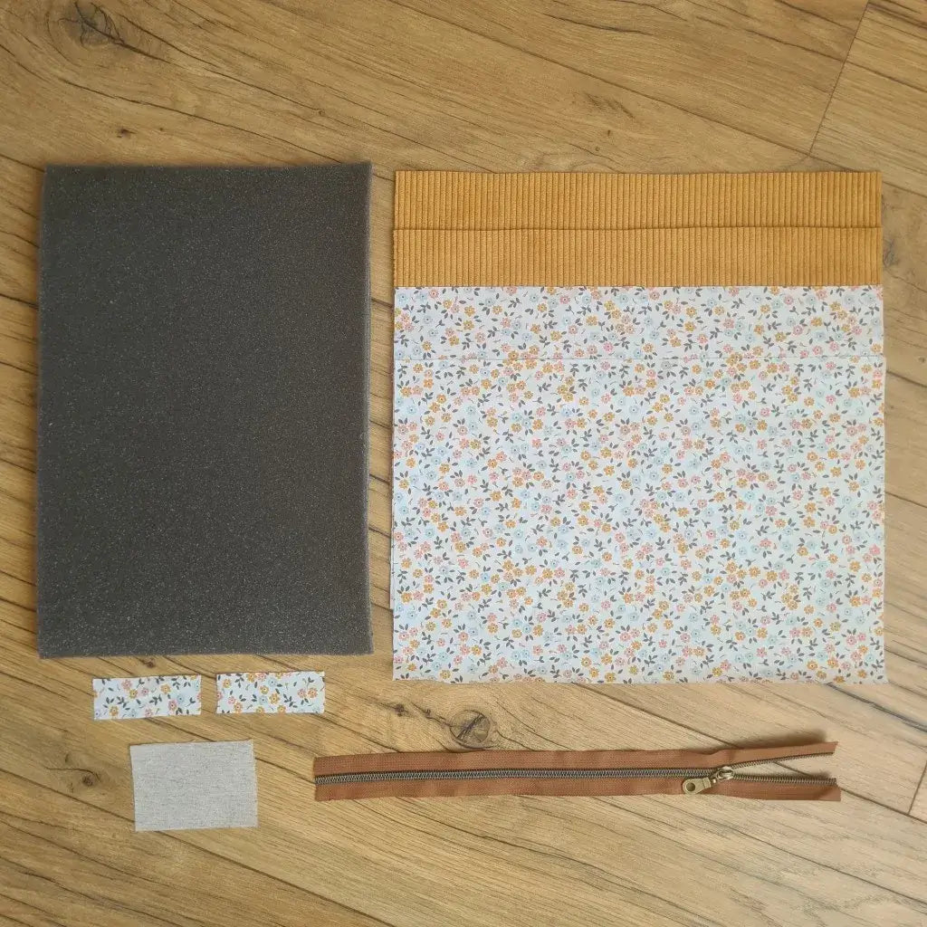 Kit "prêt à coudre" pour réaliser une housse pour tablette ou iPad en velours côtelé jaune doublée avec un tissu à motif fleurette. Ce kit couture est composé de 2 plaques en mousse, de 2 pièces en velours côtelé jaune, de 5 pièces en coton imprimé à motif fleurette et d'une fermeture éclair marron. La housse est personnalisable avec un prénom ou une inscription qui peut être floquée sur une étiquette en tissu coton et lin.