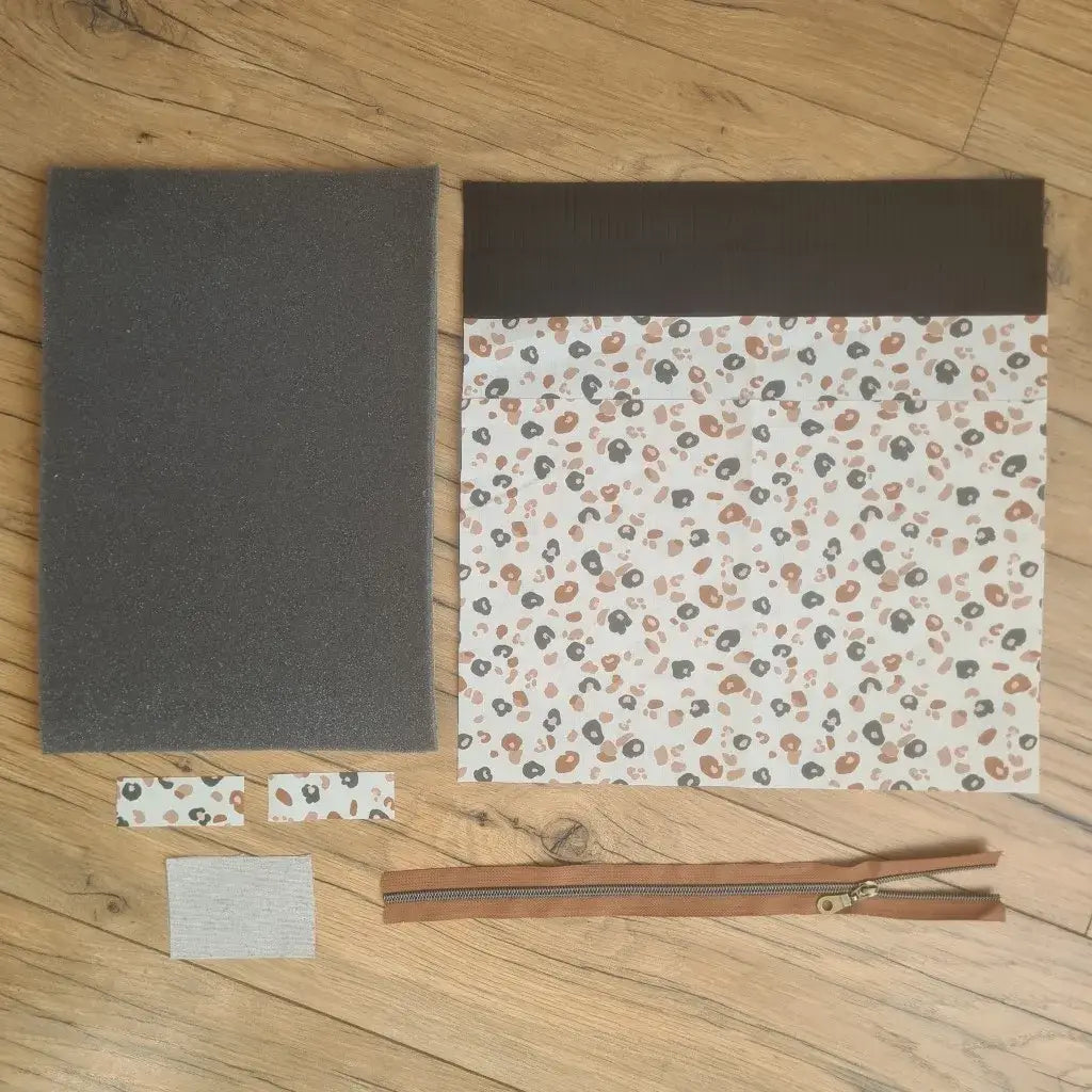Kit "prêt à coudre" pour réaliser une housse pour tablette ou iPad en velours côtelé noir doublée avec un tissu à motif léopard. Ce kit couture est composé de 2 plaques en mousse, de 2 pièces en velours côtelé noir, de 5 pièces en coton imprimé à motif léopard et d'une fermeture éclair marron. La housse est personnalisable avec un prénom ou une inscription qui peut être floquée sur une étiquette en tissu coton et lin.