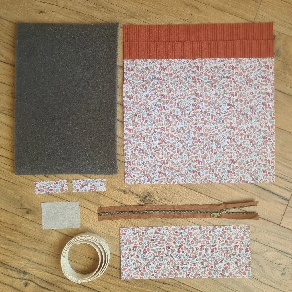 Kit "prêt à coudre" pour réaliser une housse avec anses pour tablette ou iPad en velours côtelé terracotta doublée avec un tissu à motif liberty. Ce kit couture est composé de 2 plaques en mousse, de 2 pièces en velours côtelé terracotta, de 5 pièces en coton imprimé à motif liberty, d'une fermeture éclair marron et de 2 sangles. La housse est personnalisable avec un prénom ou une inscription qui peut être floquée sur une étiquette en tissu coton et lin.