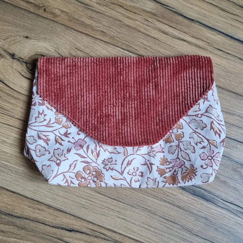 Trousse plate imperméable en tissu à inspiration orientale, ornée de motifs floraux cuivrés et d’un rabat en velours côtelé terracotta – un accessoire nomade, pratique et esthétique pour glisser petits objets, soins ou protections discrètement.