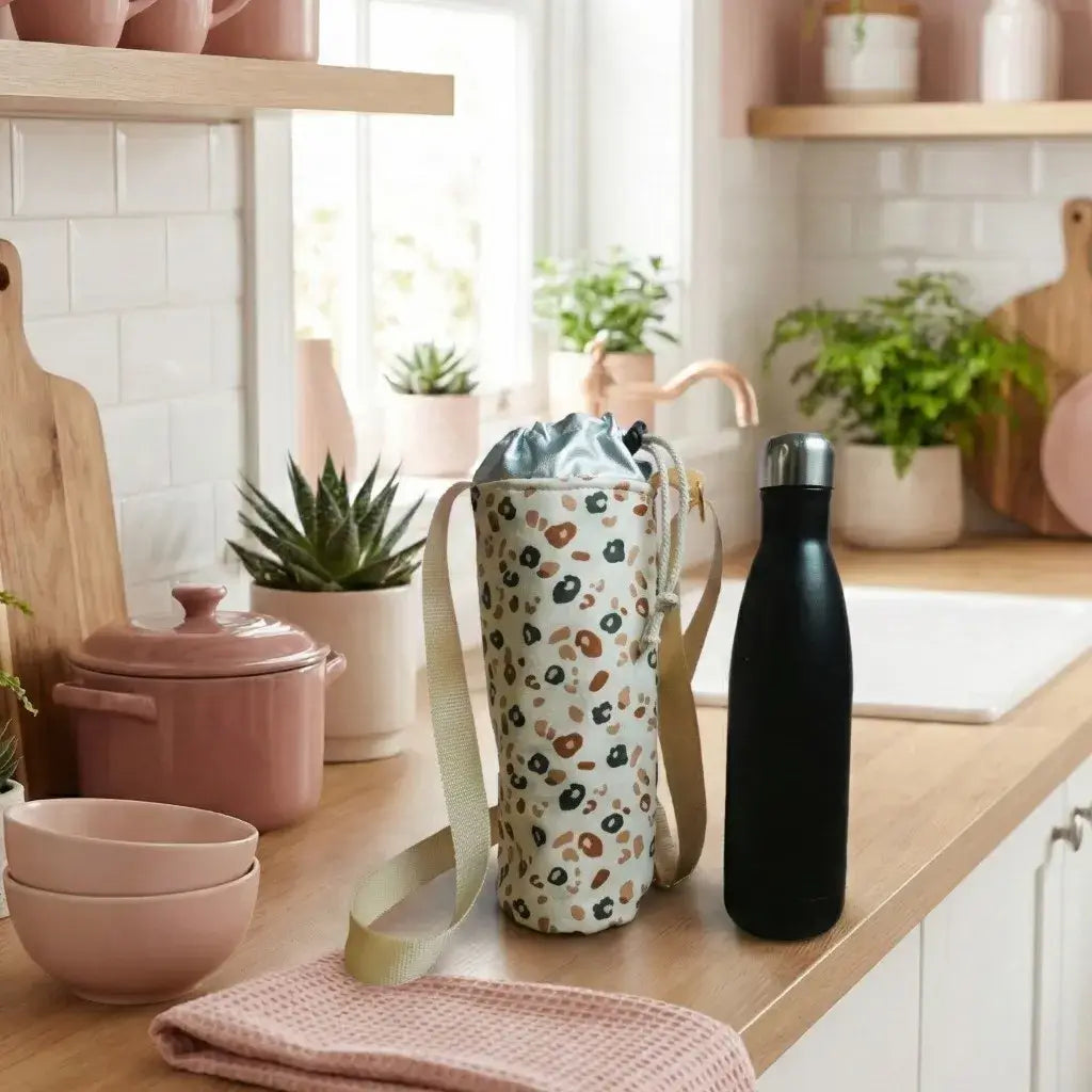 Porte-gourde isotherme motif léopard posé sur un plan de travail en bois dans une cuisine lumineuse et naturelle.