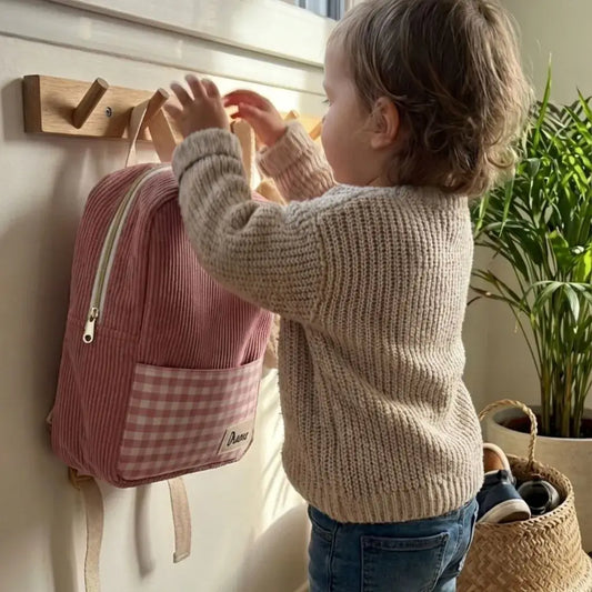 sac école maternelle enfant velours côtelé rose accroché à un porte manteau