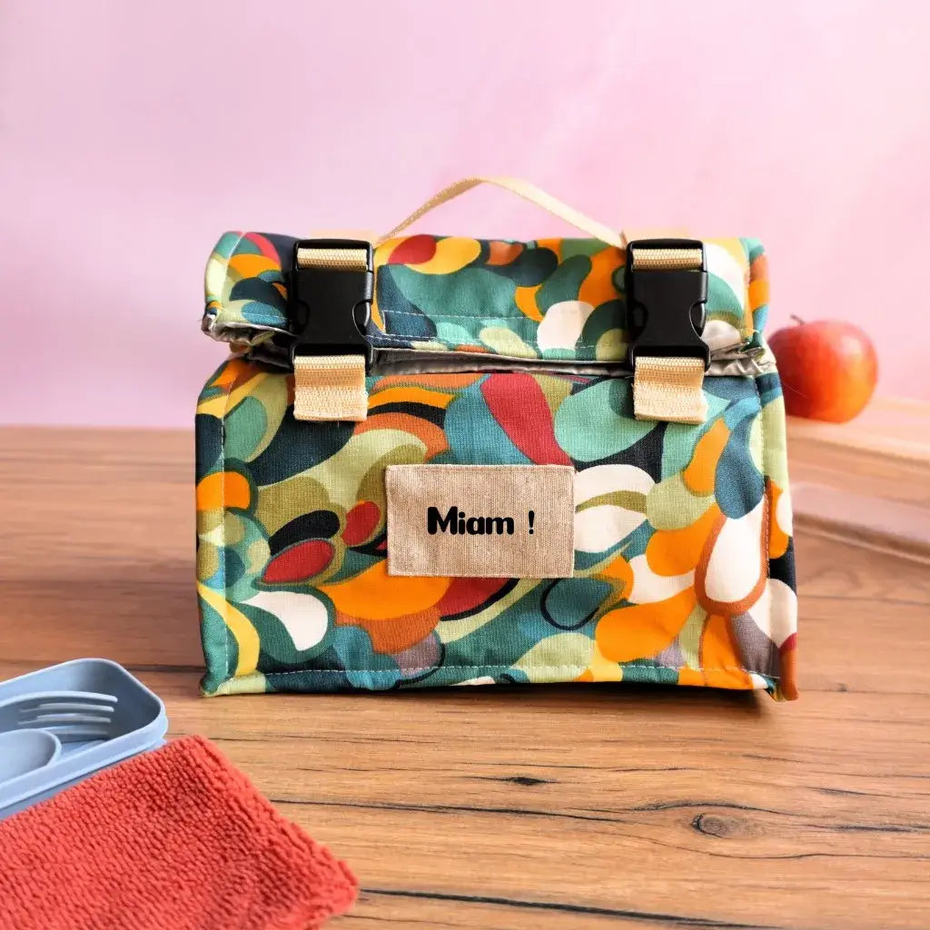 Sac repas artisanal isotherme imprimé motifs colorés rétro, décoré de l’inscription “Miam !”, équipé d’une sangle beige et de fermetures solides. Ce lunch bag pratique conserve sandwiches, fruits ou boissons à bonne température, parfait pour un usage quotidien éco-responsable.
