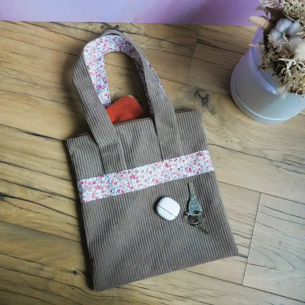Tote bag en velours côtelé taupe et tissu fleuri avec anses doublées posé sur un parquet avec des clés