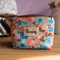 Trousse zippée personnalisée en tissu à motif floral hibiscus dans des tons corail, turquoise et marron, avec étiquette en lin floquée du prénom Fanny en noir. Accessoire artisanal pratique pour ranger maquillage, stylos ou petits objets du quotidien, cette pochette colorée associe originalité et élégance, idéale pour une utilisation scolaire, professionnelle ou en voyage.