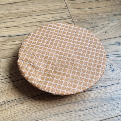 Charlotte couvre-plat rond en coton enduit réutilisable au motif carreaux. Cette charlotte alimentaire est étirée sur un bol ou une assiette creuse pouvant aller d'un diamètre de 20 à 22 cm. 