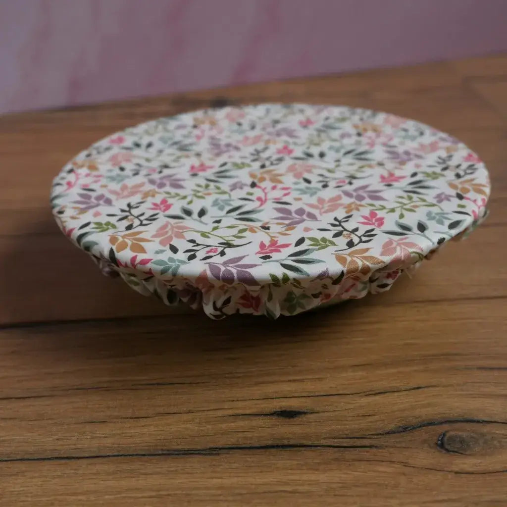 Charlotte couvre-plat élastiquée en coton enduit à motif fleuri multicolore, format moyen, idéale pour couvrir un saladier ou un plat sans film plastique. Accessoire de cuisine réutilisable et lavable, parfait pour conserver les aliments au frais ou protéger les préparations lors d’un repas extérieur.
