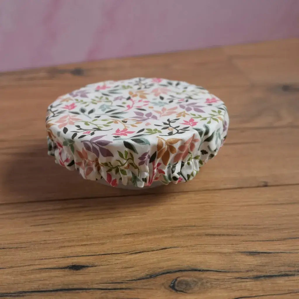 Petite charlotte couvre-plat réutilisable en coton enduit fleuri, conçue pour conserver un reste de repas ou un dessert au réfrigérateur sans film plastique. Taille S avec élastique ajustable, idéale pour couvrir un bol, une coupelle ou un yaourt maison dans une démarche zéro déchet.