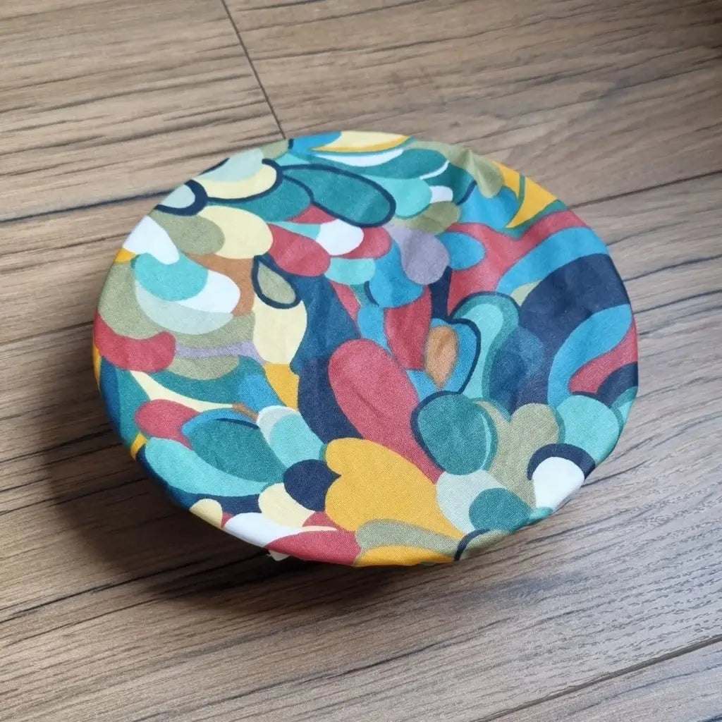 Charlotte couvre-plat rond en coton enduit réutilisable au motif splash multicolore. Cette charlotte alimentaire est étirée sur un bol ou une assiette creuse pouvant aller d'un diamètre de 20 à 22 cm. 