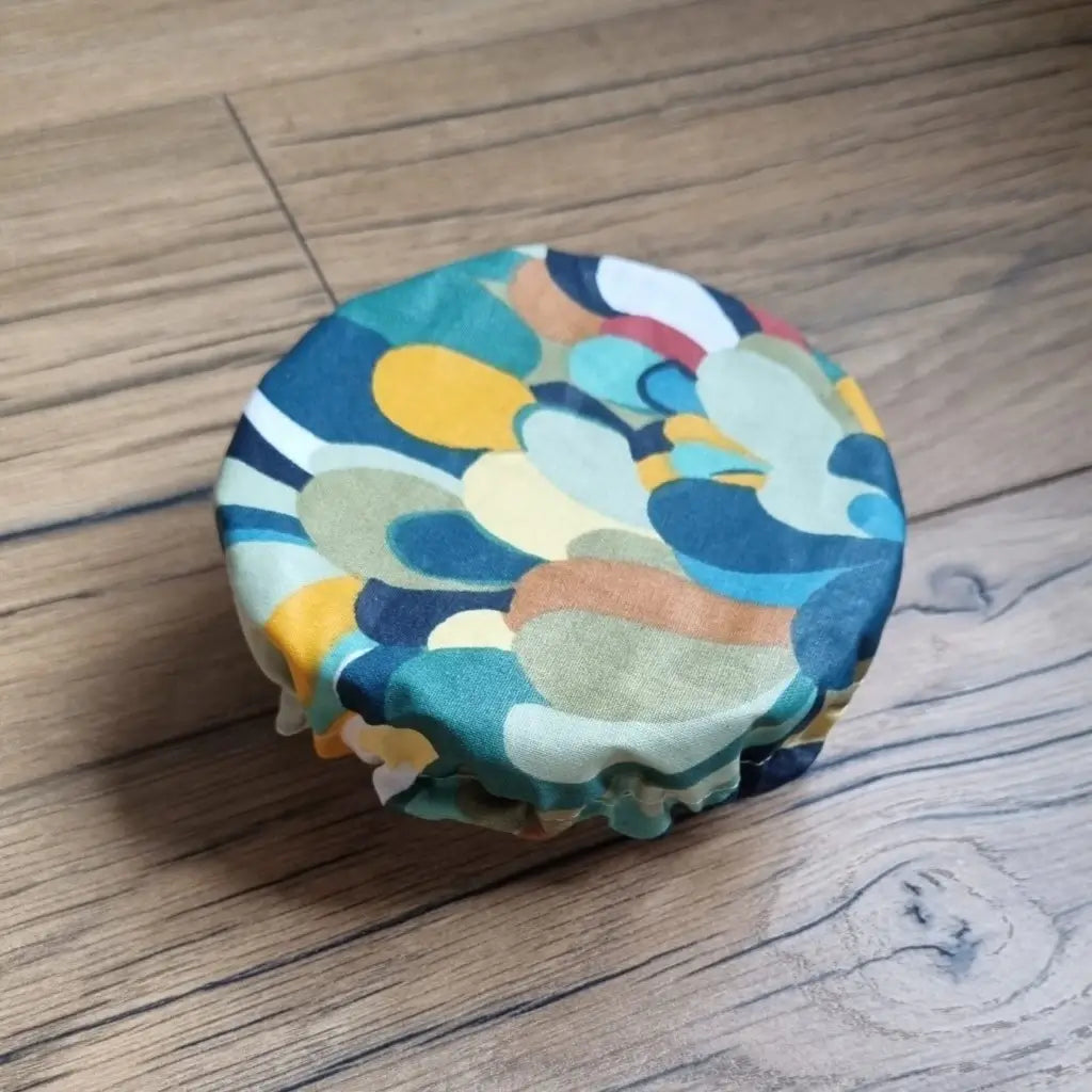 Charlotte couvre-plat rond en coton enduit réutilisable au motif splash multicolore. Cette charlotte alimentaire est étirée sur un bol pouvant aller d'un diamètre de 12 à 14 cm. 