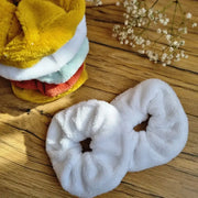 Lot de chouchous en éponge de bambou lavables et réutilisables, posés sur un sol en bois. Accessoires capillaires ultra-doux et absorbants, parfaits pour attacher les cheveux sans les abîmer ou être portés au poignet pour absorber l’humidité lors de la routine beauté. Coloris variés – blanc, moutarde, terracotta et bleu clair – pour s’adapter à tous les styles. Fabrication artisanale et respectueuse de l’environnement.