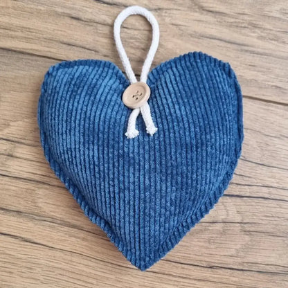 Cœur en tissu velours côtelé bleu foncé posé sur un parquet en chêne