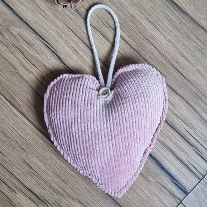 Cœur en tissu velours côtelé rose posé sur un parquet en chêne