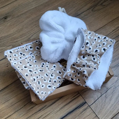 Coffret cadeau bien-être salle de bain comprenant une fleur de douche en éponge de bambou de couleur blanche, une petite lingette en éponge de bambou blanc doublée d'un tissu en coton imprimé à motif léopard, la même lingette au format maxi et un bandeau de soin également en éponge de bambou blanc et doublé avec le même tissu à motif. le tout est disposé dans un joli coffret en carton.