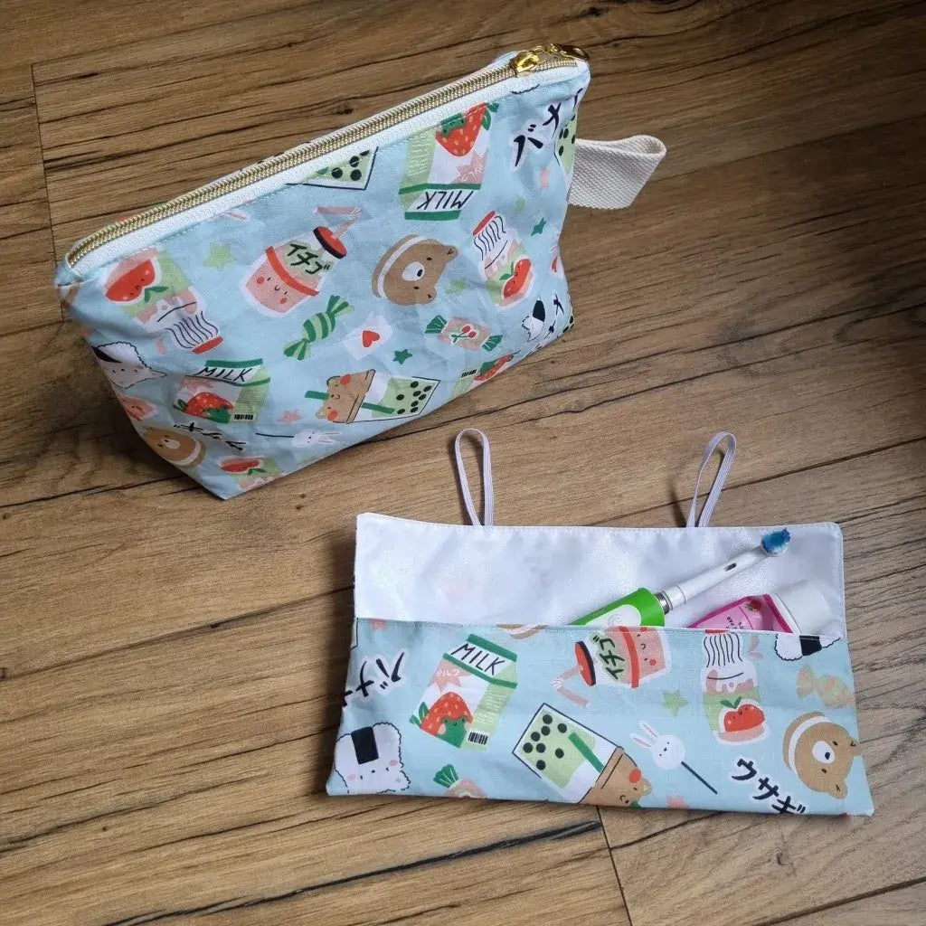 Coffret "petit baroudeur" au motif kawai. Ce coffret se compose d'une trousse de toilette imperméable à fermeture zippée et personnalisable au prénom de l'enfant, ainsi que d'un étui à brosse à dents en tissu se fermant grâce à deux petits élastiques.