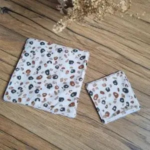 Deux lingettes en coton lavables et réutilisables disposées côte à côte. Celle de gauche est une maxi-lingette de format 18x18 cm. Celle de droite est une lingette classique de 10x10 cm. Ces deux lingettes présentent une face en coton au motif léopard.