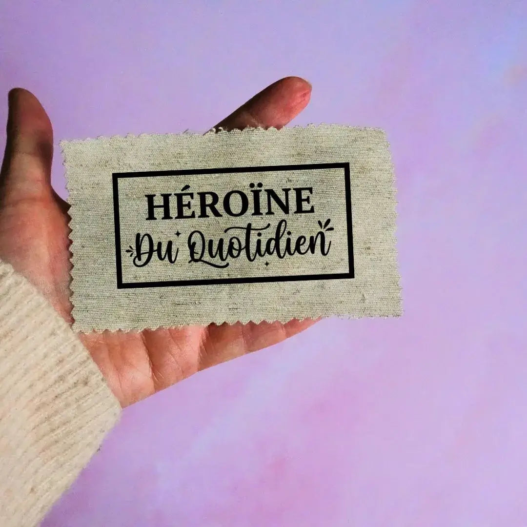 étiquette tissu beige héroïne du quotidien texte noir encadré style tampon