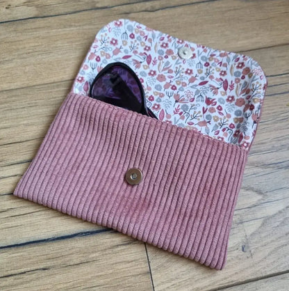 Etui à lunettes en velours côtelé de coloris rose. Cet étui est ouvert. Une paire de lunettes de soleil est à moitié glissée à l'intérieur. On distingue la doublure de cet étui à lunettes en coton imprimé à motif liberty.