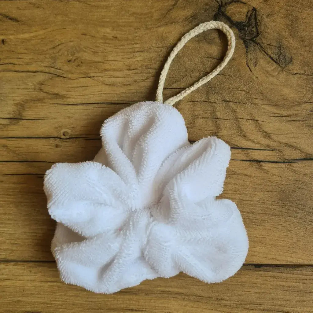 Fleur de douche lavable en éponge de bambou de coloris blanc. Cette fleur de douche est dotée d'un petit cordon en coton lui permettant d'être suspendue à la douche.