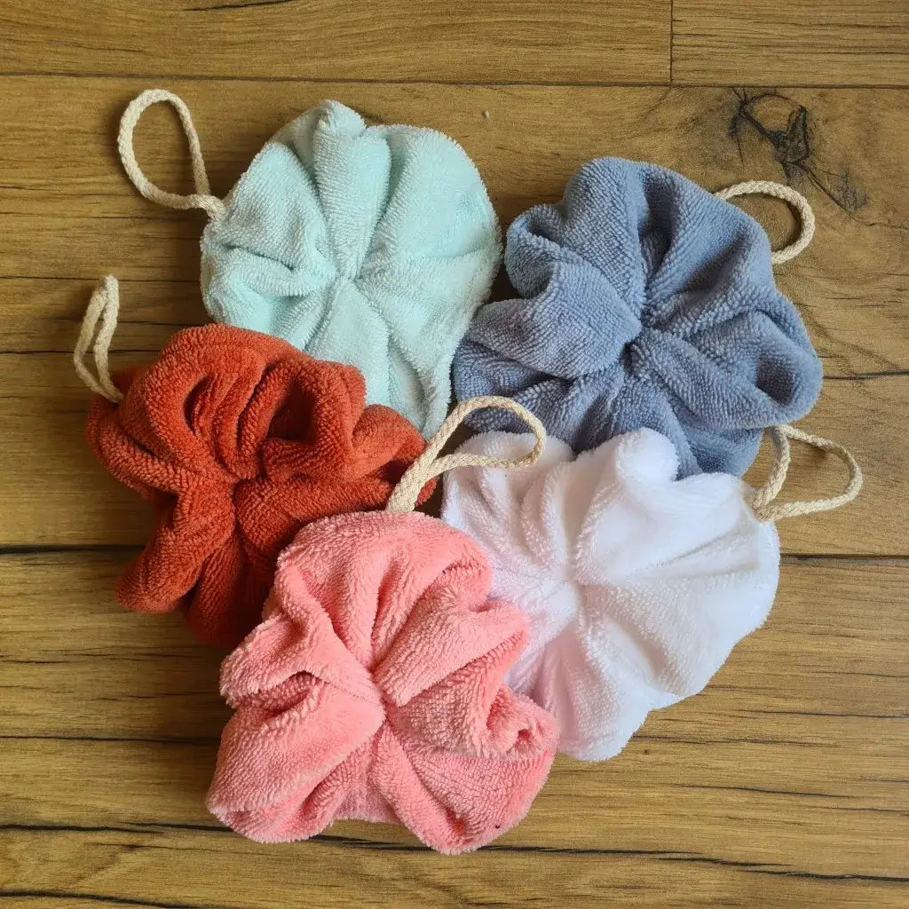 Lot de 5 fleurs de douche lavables en éponge de bambou de coloris divers. Ces fleurs de douche, dotées d'une texture douce, sont idéales pour une exfoliation quotidienne et un nettoyage en profondeur de la peau. Elles disposent d'un petit cordon en coton naturel leur permettant d'être suspendues à la douche une fois utilisées et lavées.