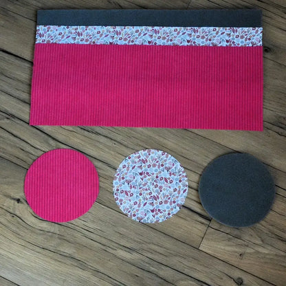 Kit couture corbeille : velours côtelé fuchsia, tissu Liberty floral et disques de mousse sur sol boisé.