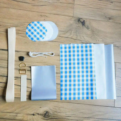 Kit couture complet pour porte-gourde isotherme motif vichy bleu : coton enduit à carreaux, isolant blanc, sangle beige et boucles dorées.