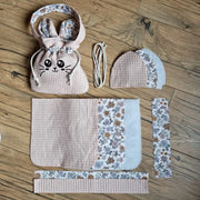 Kit couture : pièces de tissu nid d'abeille, doublure fleurie, molleton, cordon et pochon Chatoune fini sur un parquet.