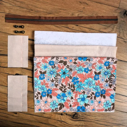 Kit couture DIY complet pour réaliser une trousse carrée à motif fleuri vintage dans les tons turquoise, corail et marron. Il comprend le tissu imprimé, la doublure, la ouate, un zip marron et deux curseurs métalliques. Ce set prêt-à-coudre est parfait pour créer une trousse personnalisée colorée et unique, idéale pour offrir ou pour ranger ses accessoires de beauté, fournitures de couture ou objets du quotidien.