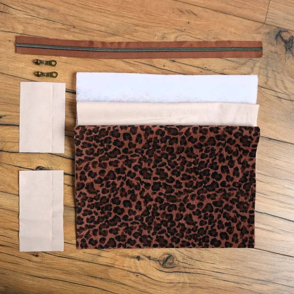 Kit couture prêt-à-coudre pour fabriquer une trousse carrée en velours côtelé imprimé léopard, fourni avec toutes les pièces nécessaires : tissu principal, doublure beige, ouate, fermeture éclair marron et curseurs métalliques. Ce kit DIY permet de créer une trousse personnalisée chic et tendance, idéale pour les amateurs de couture souhaitant confectionner un accessoire unique pour le maquillage, les stylos ou les petits objets du quotidien.