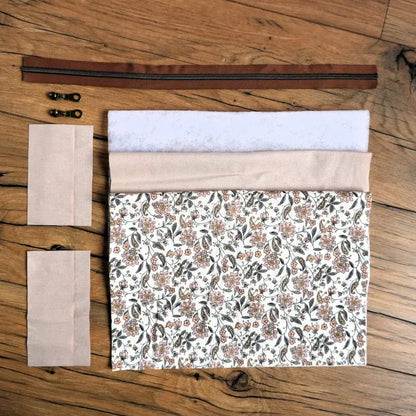 Kit couture DIY pour créer une trousse carrée à motif fleuri beige et terracotta, composé du tissu principal imprimé, d’une doublure unie, de ouate, d’une fermeture éclair marron et de deux curseurs en métal. Ce kit prêt-à-coudre est idéal pour les couturières souhaitant réaliser un accessoire raffiné et unique, parfait pour ranger maquillage, fournitures ou petits objets du quotidien.