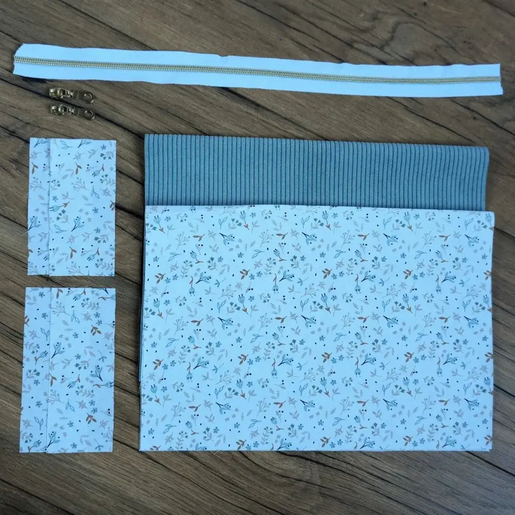 Kit couture complet pour confectionner une trousse carrée raffinée, associant un velours côtelé bleu clair et un tissu fleuri délicat aux tons pastel. Fournie avec une fermeture éclair assortie et deux curseurs métalliques, cette création DIY allie charme et praticité. Idéal pour les couturières débutantes ou confirmées souhaitant réaliser une trousse unique pour le maquillage, les produits de beauté ou les affaires de toilette.