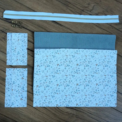 Kit couture complet pour confectionner une trousse carrée raffinée, associant un velours côtelé bleu clair et un tissu fleuri délicat aux tons pastel. Fournie avec une fermeture éclair assortie et deux curseurs métalliques, cette création DIY allie charme et praticité. Idéal pour les couturières débutantes ou confirmées souhaitant réaliser une trousse unique pour le maquillage, les produits de beauté ou les affaires de toilette.