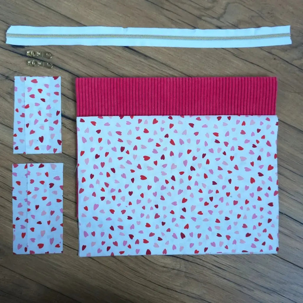 Kit couture créatif pour réaliser une trousse carrée originale, combinant un velours côtelé framboise et un tissu imprimé de petits cœurs rouges et roses. Le set comprend une fermeture éclair blanche, deux curseurs dorés et toutes les pièces de tissu nécessaires. Un projet DIY facile et plein de charme, parfait pour offrir ou s’initier à la couture avec un résultat doux, coloré et plein d’amour.
