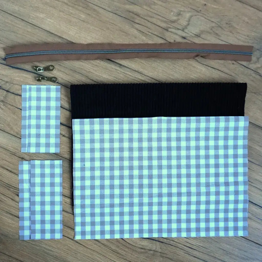 Kit couture DIY pour fabriquer une trousse carrée moderne, associant un velours côtelé noir profond à un tissu vichy gris et blanc. Le lot comprend une fermeture éclair marron, deux curseurs métalliques et toutes les pièces de tissu pré-découpées. Un projet accessible pour créer une trousse élégante et intemporelle, idéale pour un usage quotidien ou comme cadeau fait main personnalisé.