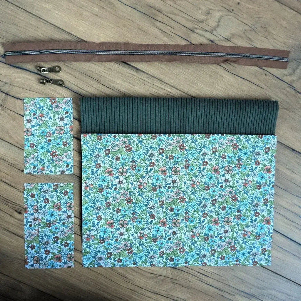Kit couture DIY pour réaliser une trousse carrée au charme naturel, associant un velours côtelé vert à un tissu fleuri aux tons bleus, verts et bruns. Ce set comprend une fermeture éclair marron, deux curseurs métalliques et les pièces de tissu déjà découpées aux bonnes dimensions. Un projet accessible et inspirant pour créer une trousse artisanale élégante, parfaite pour y ranger ses affaires de toilette ou pour en faire un cadeau fait main.