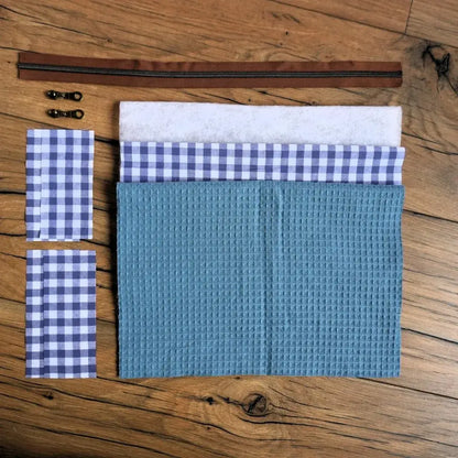 Kit prêt-à-coudre pour fabriquer une trousse carrée en nid d’abeille bleu denim avec doublure à carreaux vichy bleu et blanc. Le kit comprend les coupons de tissus, la ouate, la fermeture éclair marron et les curseurs assortis. Ensemble complet pour créer une trousse artisanale chic et durable, parfaite pour ranger maquillage, stylos ou accessoires de couture. Idéal pour un projet DIY simple et élégant.