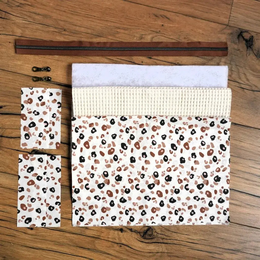 Kit couture complet pour créer une trousse carrée en nid d’abeille beige naturel avec doublure imprimée léopard beige, noir et marron. Le kit comprend les coupons de tissu, la ouate, la fermeture éclair marron assortie et les curseurs métalliques. Un projet de couture moderne et facile à réaliser, idéal pour fabriquer une trousse personnalisée au style tendance et intemporel.