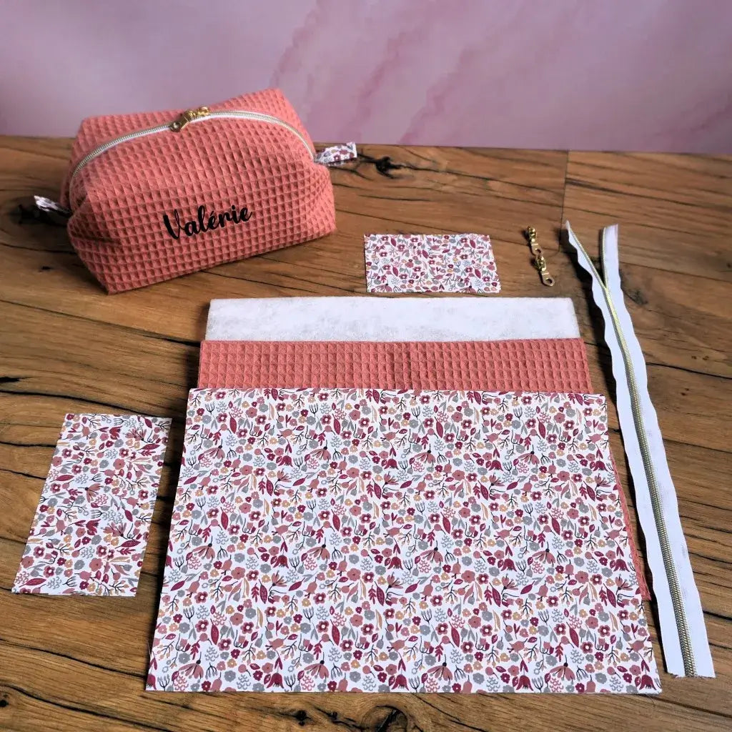 Kit couture complet pour réaliser une trousse carrée personnalisée en nid d’abeille marsala avec doublure fleurie. Le kit comprend le tissu principal texturé, la doublure coton imprimé, la ouate, la fermeture éclair dorée et toutes les pièces prédécoupées. Exemple fini visible avec prénom floqué “Valérie”. Idéal pour les couturières débutantes ou confirmées souhaitant créer une trousse faite main élégante et pratique.