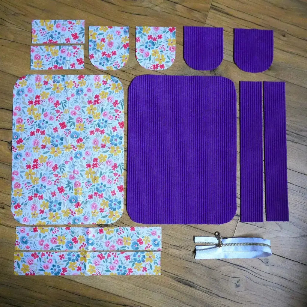 Éléments de trousse à coudre en velours violet intense et doublure coton à fleurs avec fermeture éclair blanche.