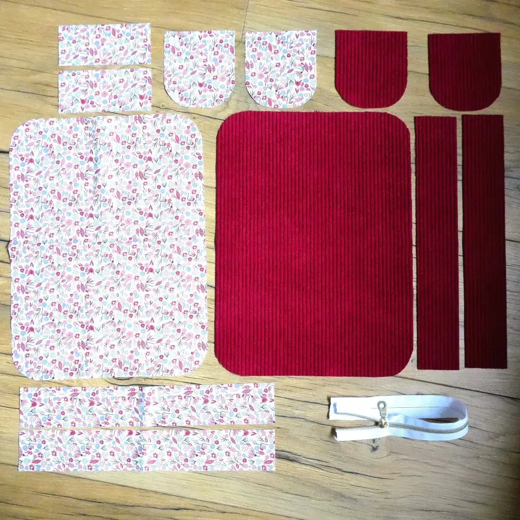 Kit trousse : pièces en velours bordeaux et tissu fleuri romantique avec fermeture éclair blanche sur parquet.