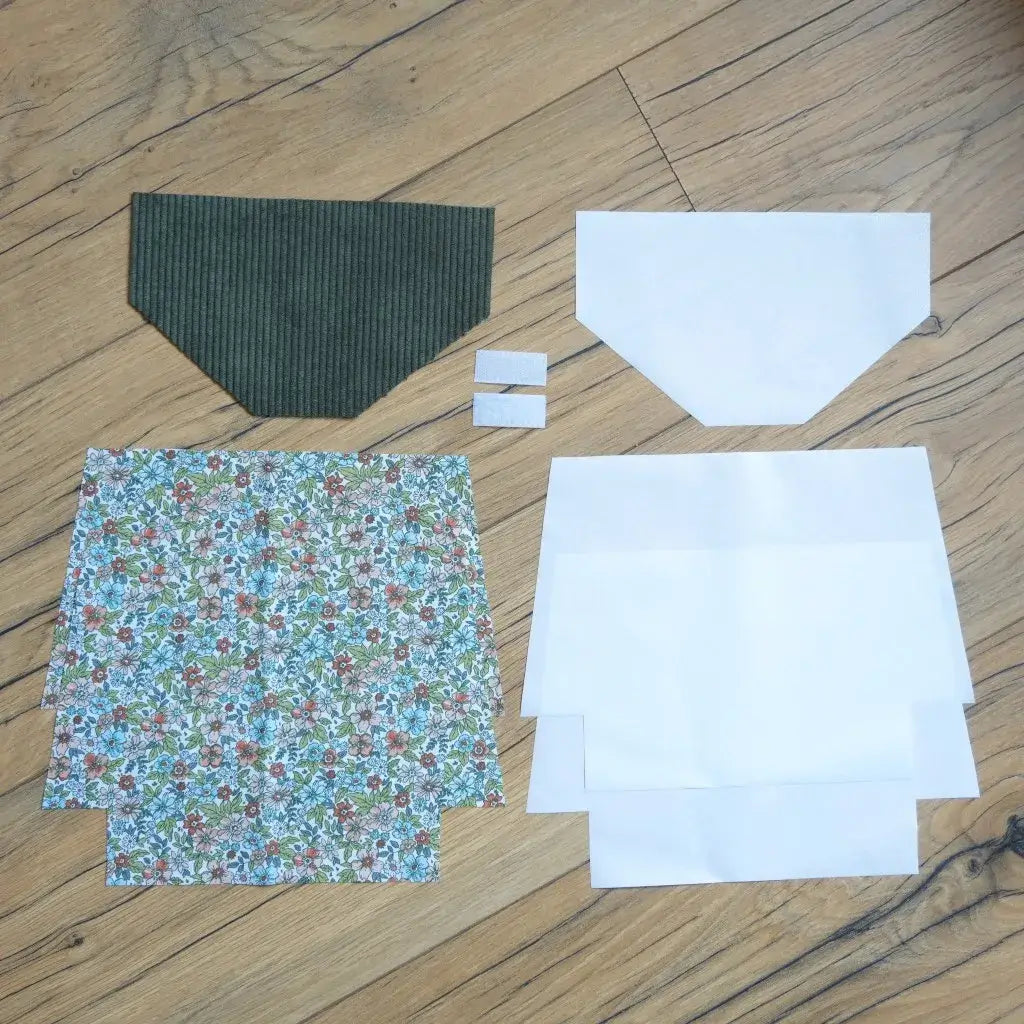 Kit couture DIY pour fabriquer une pochette à scratch imperméable, comprenant un rabat en velours côtelé vert, des coupons de coton imprimé fleuri aux tons bleus, rouges et verts, des doublures blanches et deux scratchs. Ce kit prêt-à-coudre complet permet de créer une trousse élégante et résistante, idéale pour un projet créatif personnalisé ou comme cadeau fait main.