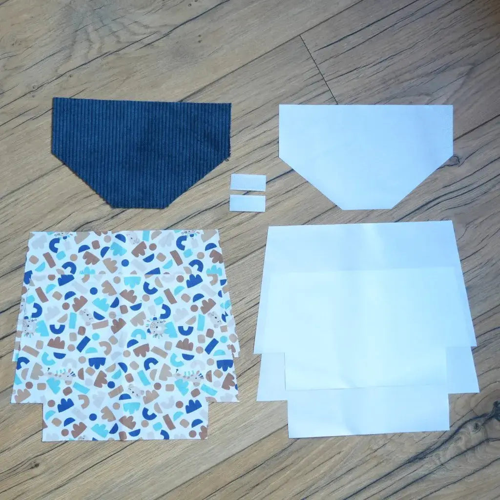 Kit couture prêt-à-coudre pour réaliser une pochette à scratch imperméable, comprenant un rabat en velours côtelé bleu marine, des coupons de coton imprimé aux motifs abstraits bleu, beige et marron, des doublures blanches et deux scratchs. Ce kit DIY complet permet de confectionner une trousse personnalisée, résistante et moderne, parfaite pour un projet créatif ou un cadeau fait main.