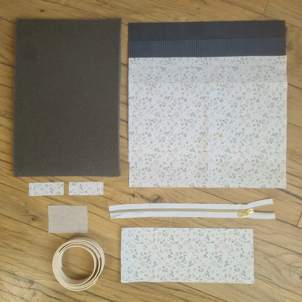 Kit "prêt à coudre" pour réaliser une housse avec anses pour tablette ou iPad en velours côtelé bleu foncé doublée avec un tissu à motif azra. Ce kit couture est composé de 2 plaques en mousse, de 2 pièces en velours côtelé bleu foncé, de 5 pièces en coton imprimé à motif azra, d'une fermeture éclair blanche et de 2 sangles. La housse est personnalisable avec un prénom ou une inscription qui peut être floquée sur une étiquette en tissu coton et lin.