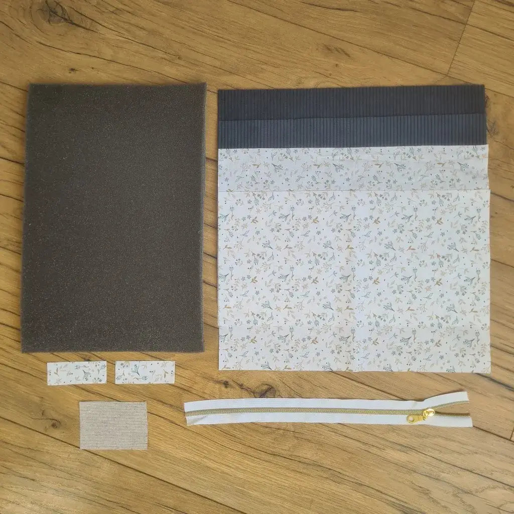 Kit "prêt à coudre" pour réaliser une housse pour tablette ou iPad en velours côtelé bleu foncé doublée avec un tissu à motif azra. Ce kit couture est composé de 2 plaques en mousse, de 2 pièces en velours côtelé bleu foncé, de 5 pièces en coton imprimé à motif azra et d'une fermeture éclair blanche. La housse est personnalisable avec un prénom ou une inscription qui peut être floquée sur une étiquette en tissu coton et lin.