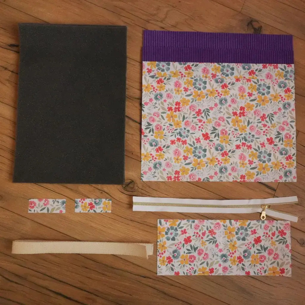 Kit de couture pour pochette tablette : tissus fleuris, tissu uni lavande, mousse de renfort, fermeture éclair et sangle.