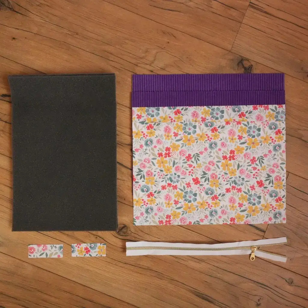 Kit couture housse tablette : velours côtelé lavande, tissu fleuri, mousse et fermeture éclair sur fond bois.
