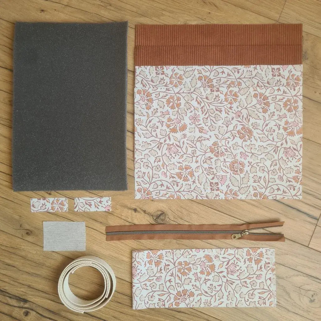 Kit "prêt à coudre" pour réaliser une housse avec anses pour tablette ou iPad en velours côtelé terracotta doublée avec un tissu à motif oriental. Ce kit couture est composé de 2 plaques en mousse, de 2 pièces en velours côtelé terracotta, de 5 pièces en coton imprimé à motif oriental, d'une fermeture éclair marron et de 2 sangles. La housse est personnalisable avec un prénom ou une inscription qui peut être floquée sur une étiquette en tissu coton et lin.